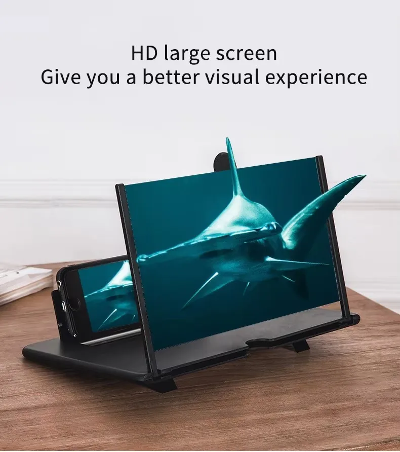 Amplificador de pantalla 3D negro para celular sobre mesa de madera mostrando un tiburón en la proyectada.