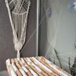 Hamaca para gato beige con textura acanalada, suspendida de un ventanal mediante ventosas y cuerdas finas para aprovechar el espacio vertical.