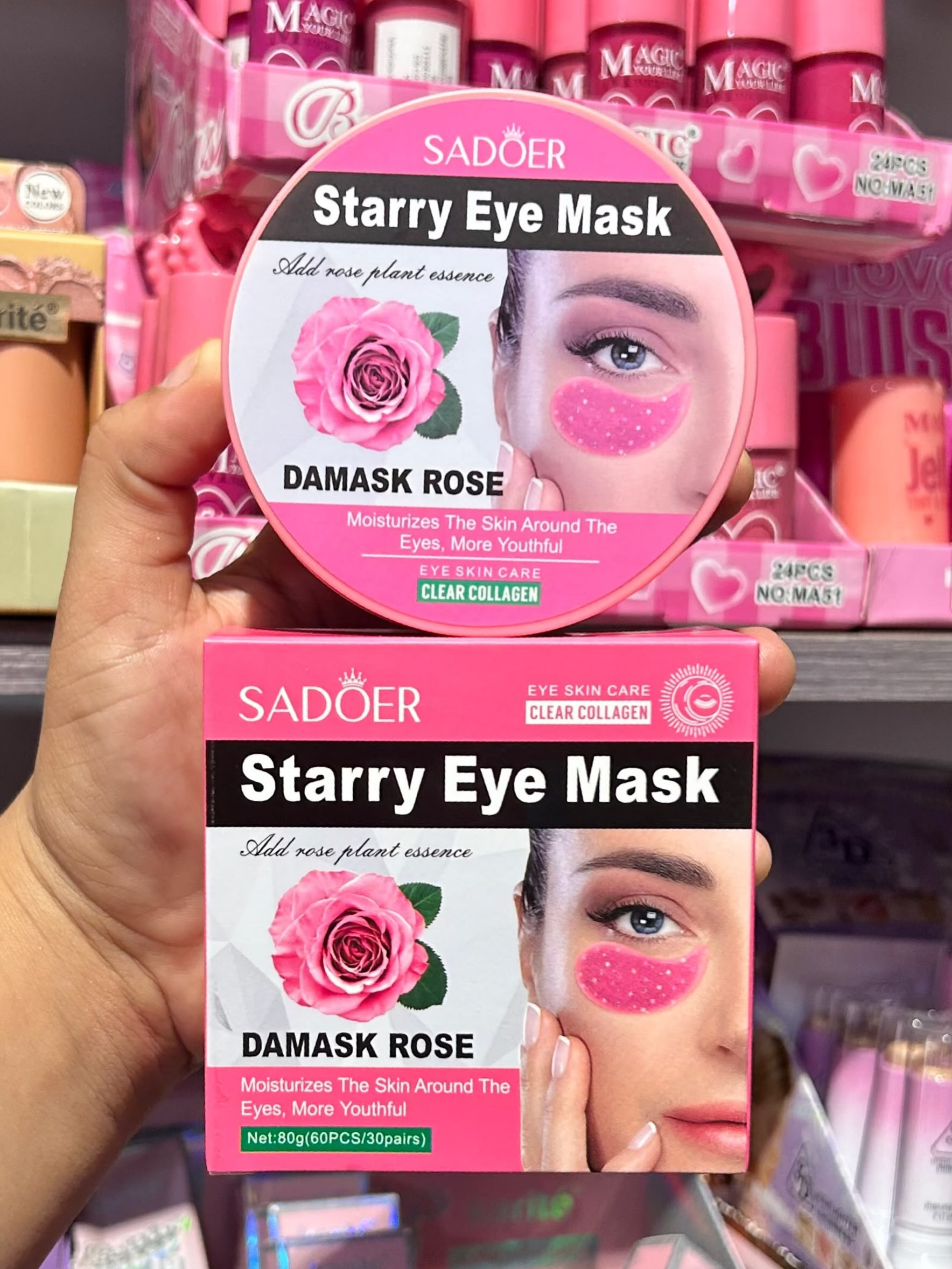 Mano sosteniendo caja y envase redondo rosados de parches de hidrogel de colágeno Sadoer con extracto de rosa para contorno de ojos.