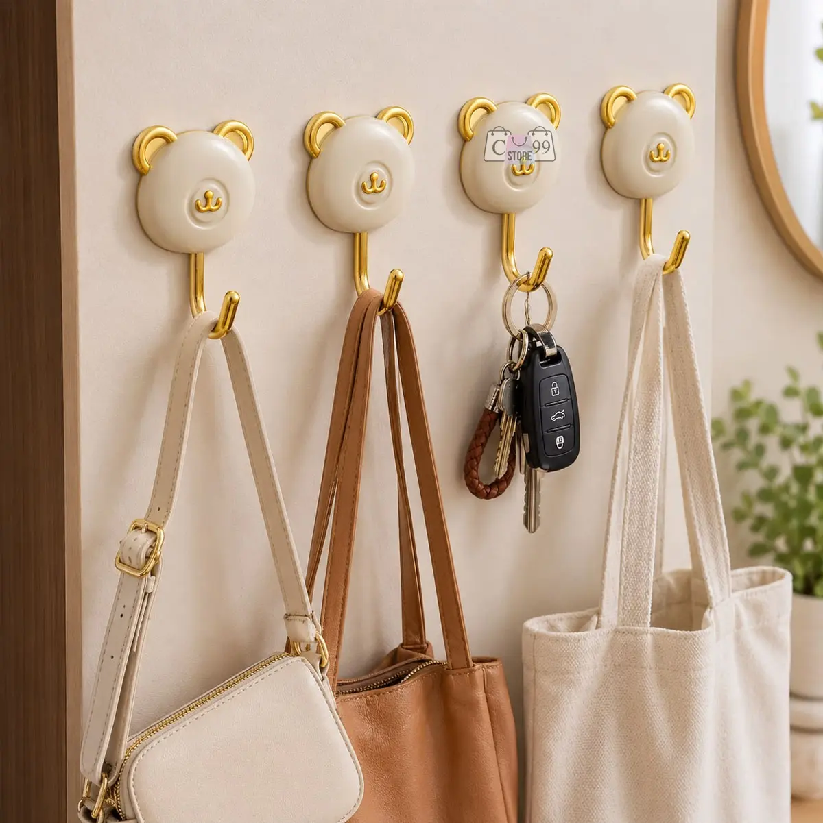 Percheros adhesivos decorativos de oso color crema con detalles y ganchos dorados, organizando bolsos y llaves en una pared neutra.