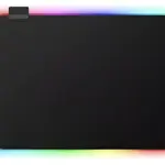 Tapete para escritorio negro con iluminación LED perimetral multicolor arcoíris y conector en la esquina superior izquierda.