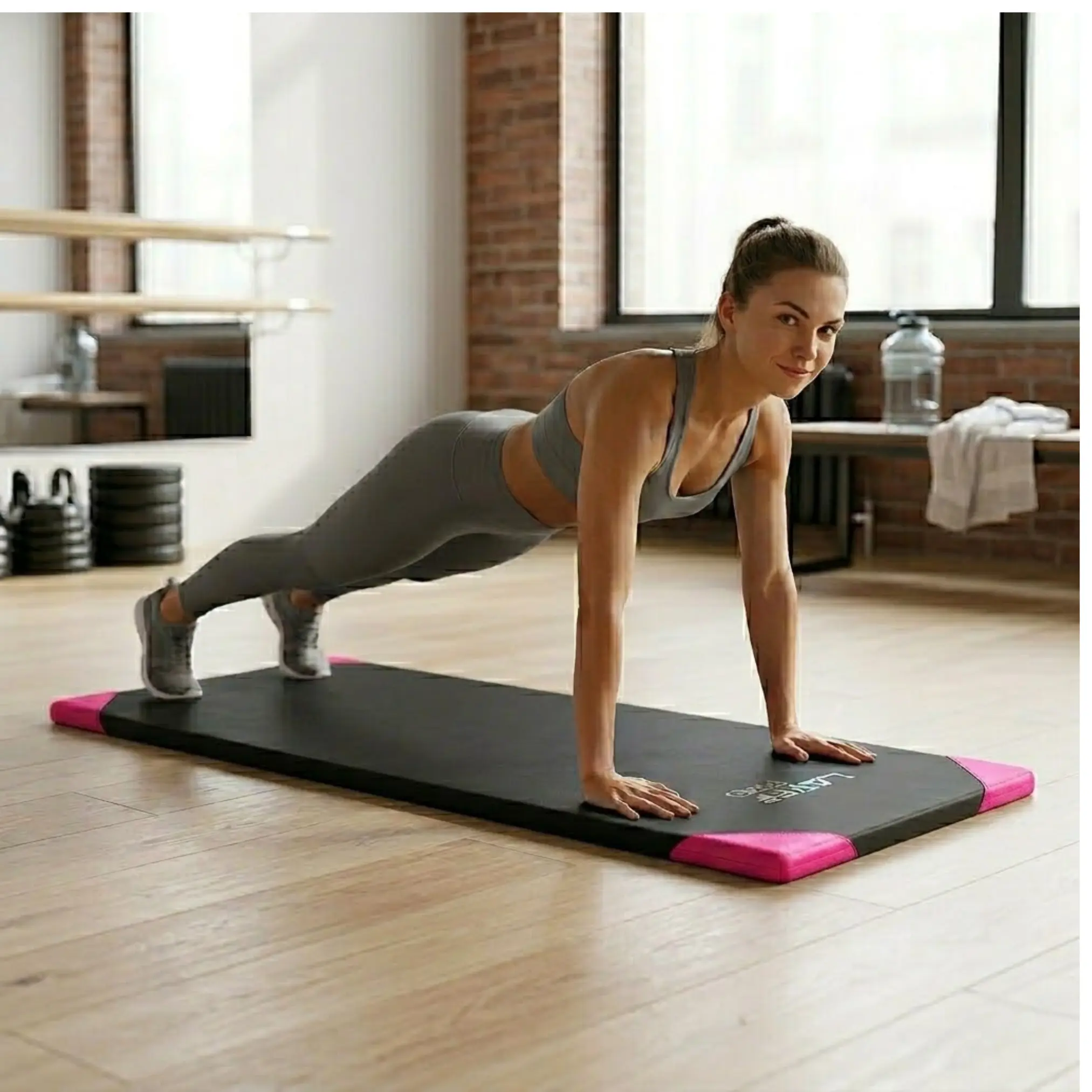 Colchoneta deportiva negra de alta densidad con esquinas fucsias sobre piso de madera, usada por mujer haciendo plancha.