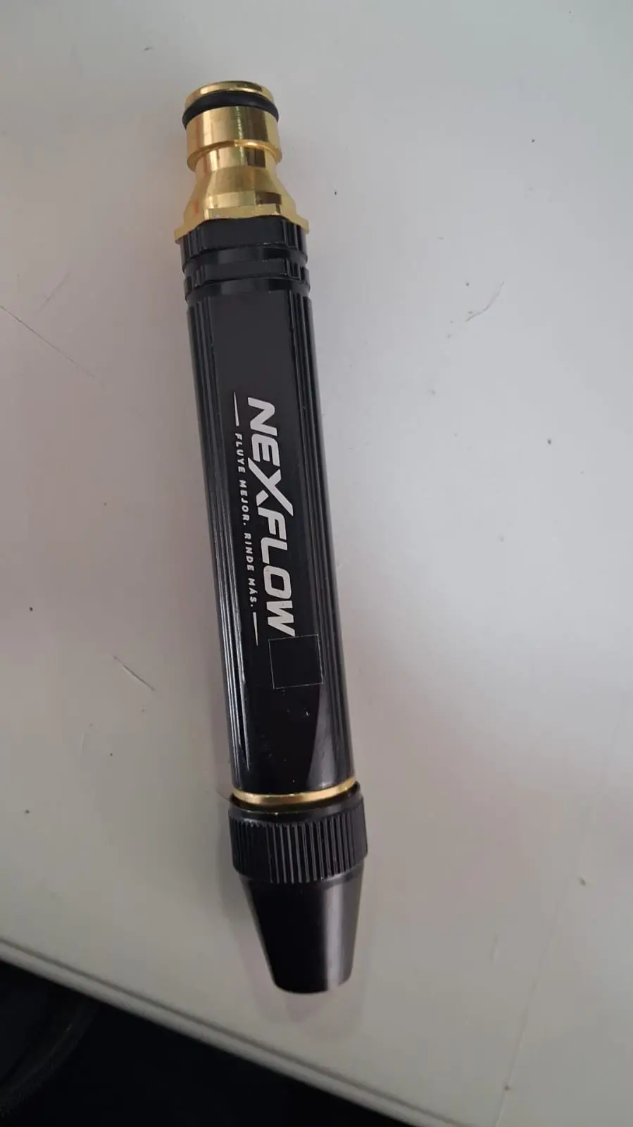 Boquilla pulverizadora ajustable negra y dorada para manguera de jardín, con cuerpo estriado y conector rápido superior.