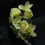 Manojo de rosas artificiales beige y flores de pétalos claros con follaje verde para decoración elegante sobre fondo negro.