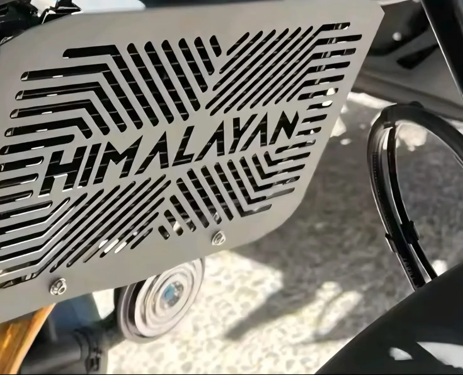 Protector de radiador en acero inoxidable para Himalayan 450 con diseño calado geométrico y la palabra HIMALAYAN en el centro.