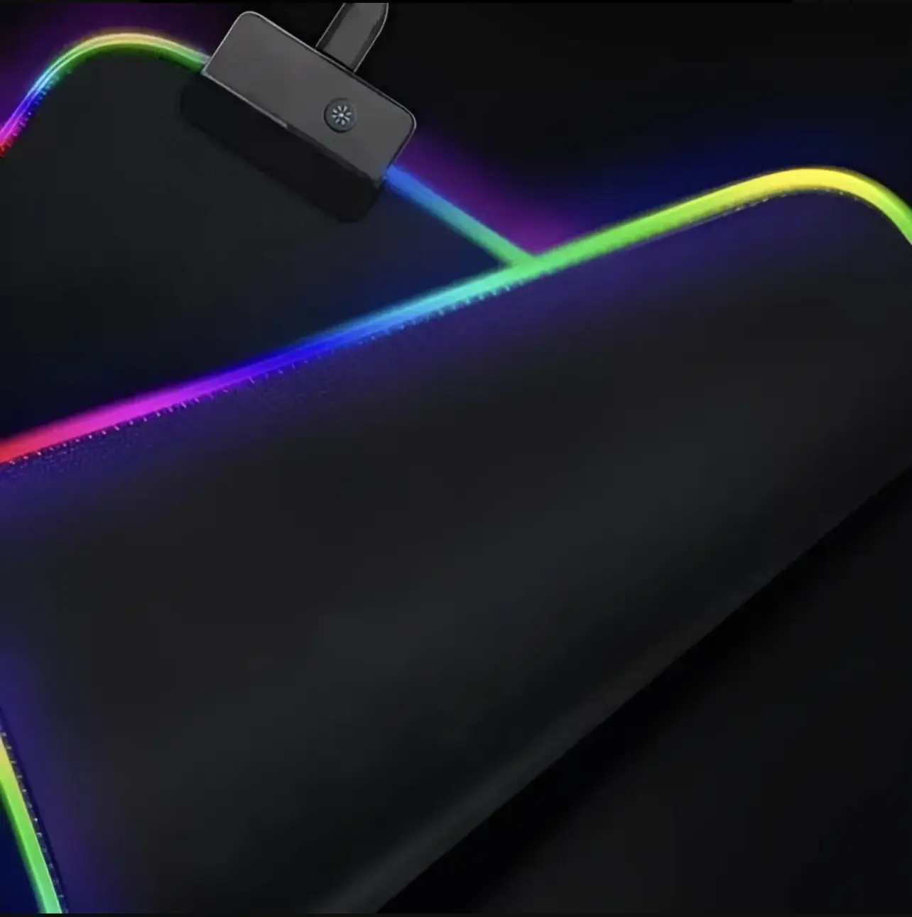 Tapete negro para escritorio con bordes de luces LED RGB en degradado multicolor, superficie lisa y conector USB visible en primer plano.