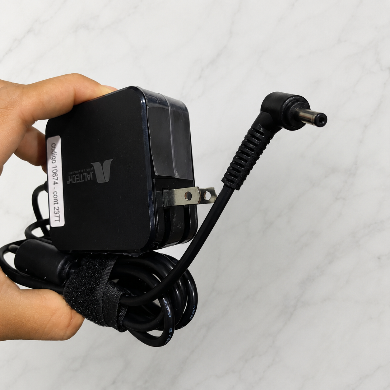 Cargador Asus negro de 19V 2.37A con conector de punta recta y cable enrollado con banda de velcro, sostenido por una mano.