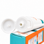 Tubo de protector solar SPF 50 abierto con tapa abatible, sobre su caja naranja y turquesa que destaca Ácido Hialurónico, Vitamina E y contenido de 50 g.