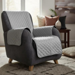 Protector acolchado gris para sillón de un puesto con fundas para brazos, sobre sillón oscuro en sala