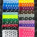 Pañoletas para perros apiladas en múltiples colores brillantes con estampado de huellas blancas y costuras en los bordes.