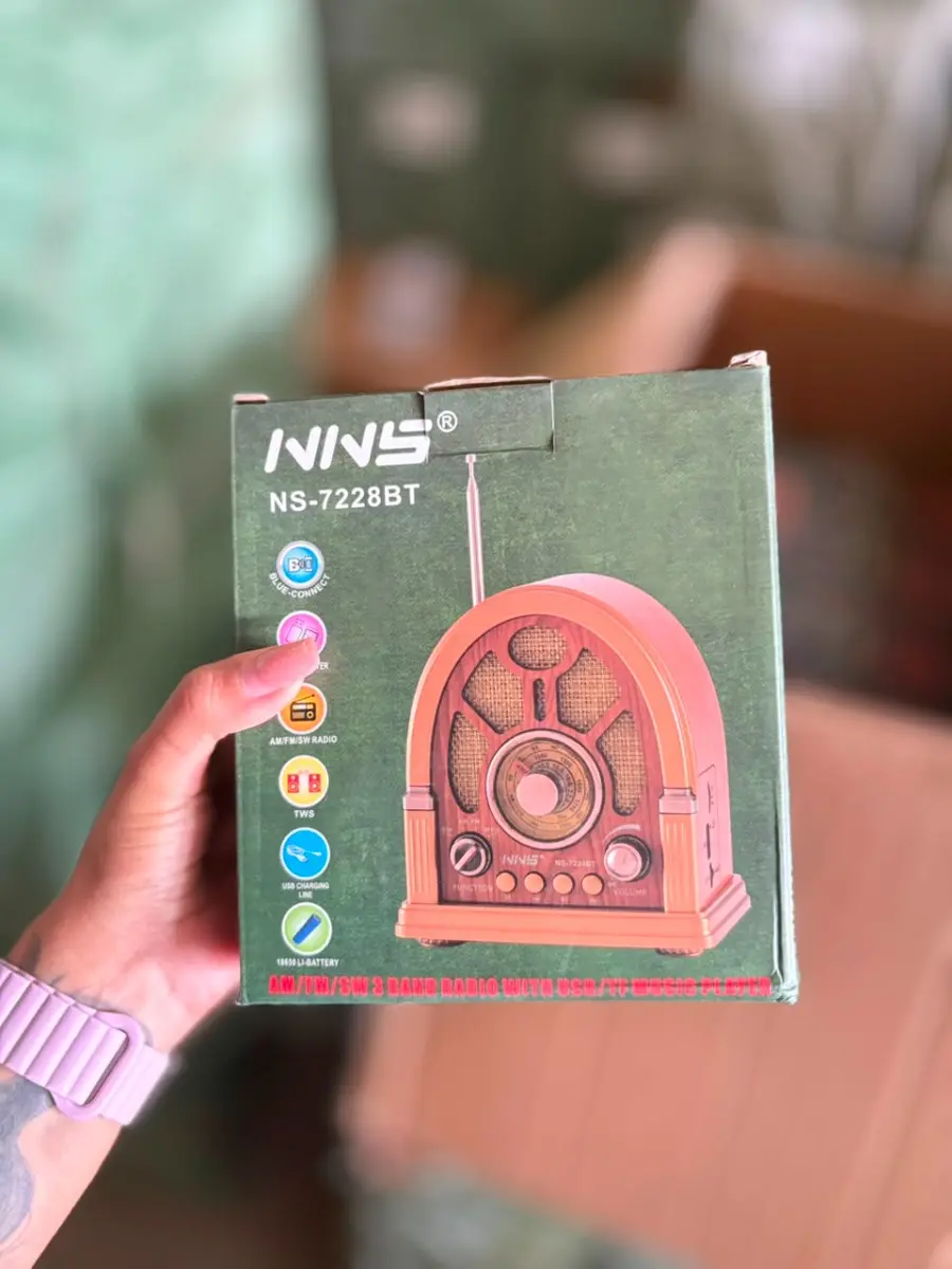 Mano sosteniendo caja verde de radio retro portátil con Bluetooth en acabado de madera y antena retráctil.