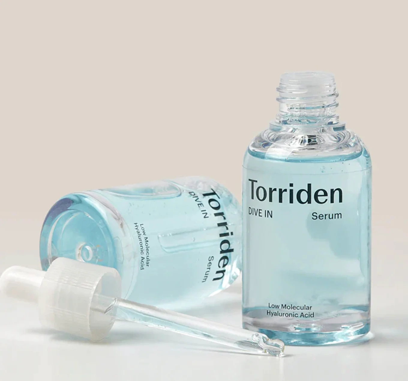 Dos botellas de sérum facial hidratante Torriden de 30 ml con ácido hialurónico, una de pie destapada y otra acostada junto al gotero.