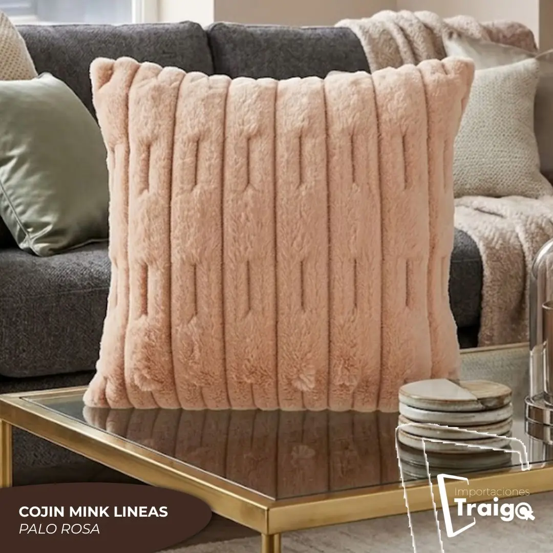 Cojín decorativo de 45x45 cm en tela mink color palo rosa con textura de líneas en relieve, ubicado sobre una mesa de centro frente a un sofá gris.