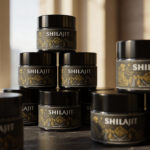 Pila de tarros negros de Shilajit con etiqueta dorada y diseño de montañas, sobre superficie oscura.