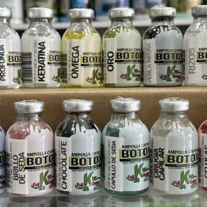 Dos filas de ampollas de botox capilar con variaciones de color y etiquetas con nombres como Vitamina C y Chocolate, exhibidas sobre una caja de cartón.