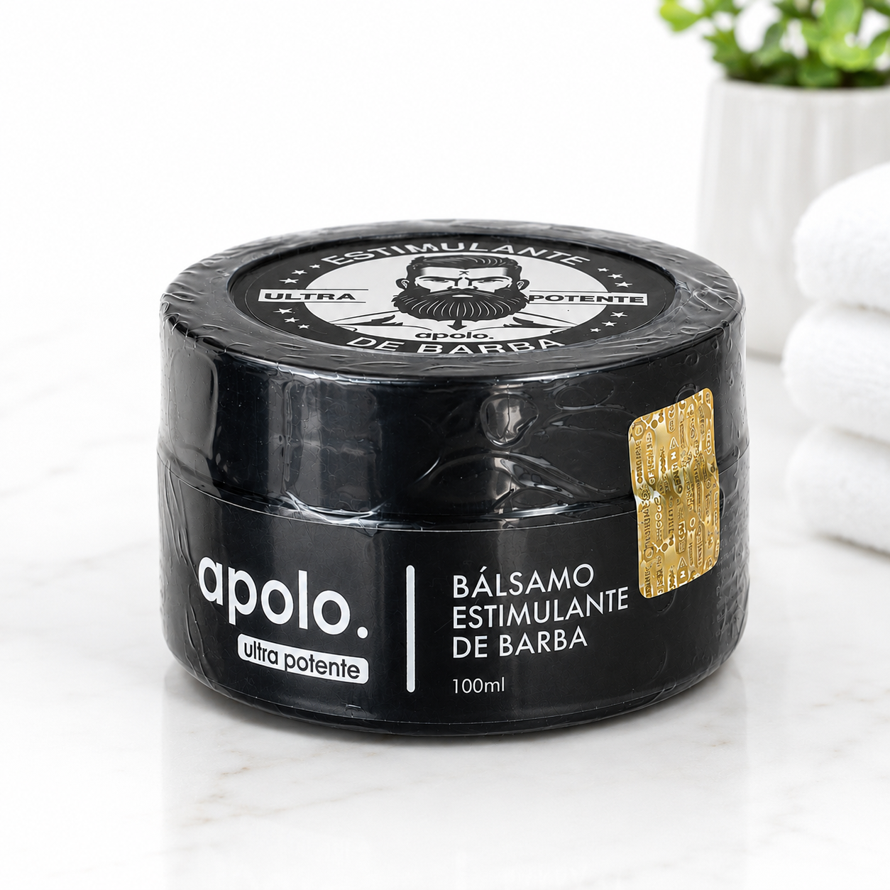 Bálsamo estimulante de barba Apolo ultra potente en envase negro de 100ml con sello dorado, sobre superficie de mármol blanco.