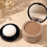 Compacto de polvo para el cabello LANLSLO tono marrón con espejo abierto y esponja blanca en tapa negra, sobre fondo beige texturizado.
