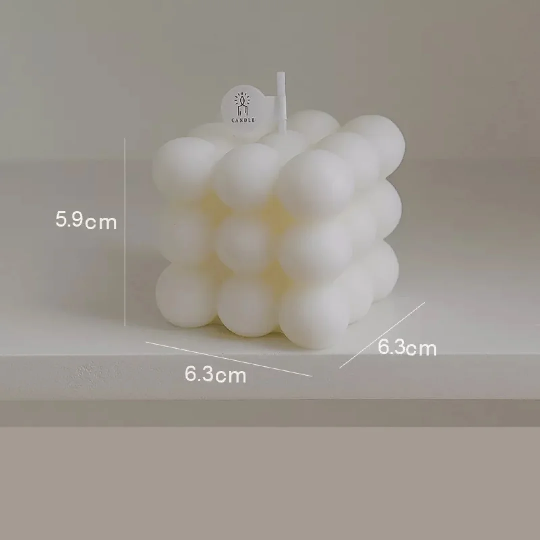 Vela aromática bubble blanca de cera con diseño geométrico de cubos, medidas 5.9 cm de alto por 6.3 cm de ancho y fondo, con mecha y etiqueta decorativa.