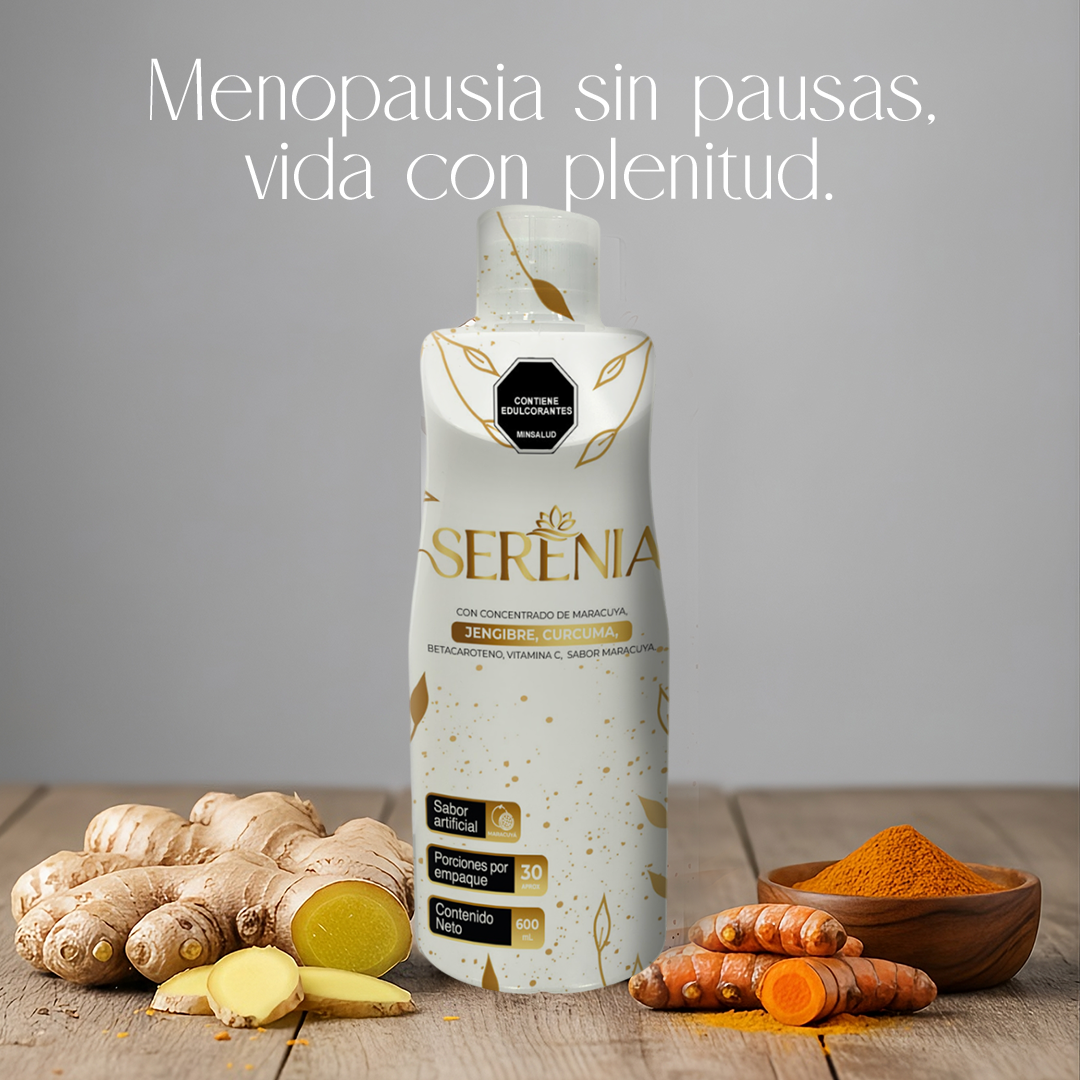 Botella blanca de 600 ml con detalles dorados de bebida natural, rodeada de jengibre fresco y cúrcuma en polvo sobre mesa de madera.
