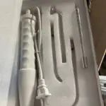 Varita facial de alta frecuencia blanca con cable y tres electrodos de vidrio de distintas formas dispuestos en su caja organizadora de espuma protectora.