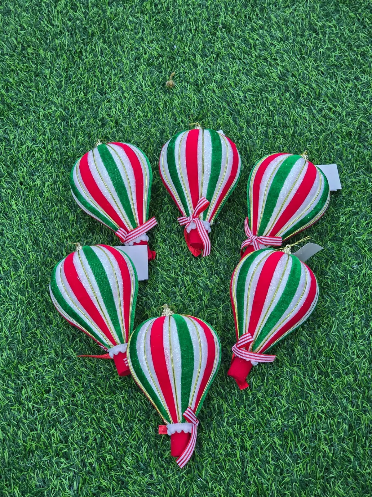 Set de cinco adornos navideños colgantes con forma de globo aerostático, decorados con franjas verticales rojas, verdes y blancas con acabado brillante.