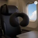Almohada de viaje en U negra Intex inflable con textura suave para cuello, suspendida en la cabina de un avión junto a una ventanilla.