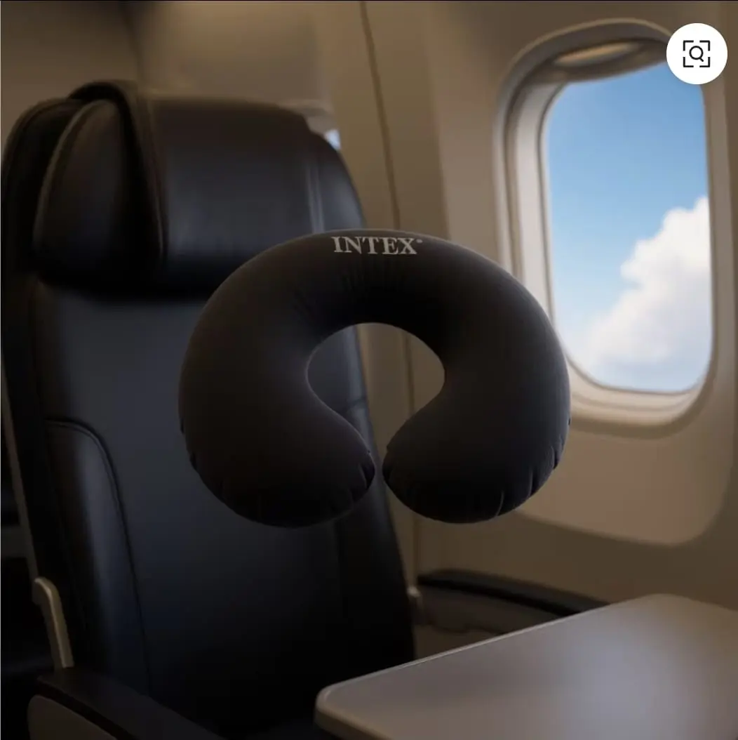 Almohada de viaje en U negra Intex inflable con textura suave para cuello, suspendida en la cabina de un avión junto a una ventanilla.