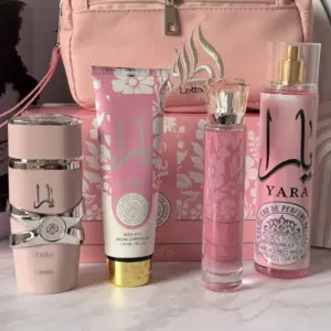 Set de belleza Yara en tonos rosa con cosmetiquera, crema, perfume y fragancia con detalles dorados y plateados sobre fondo de mármol.