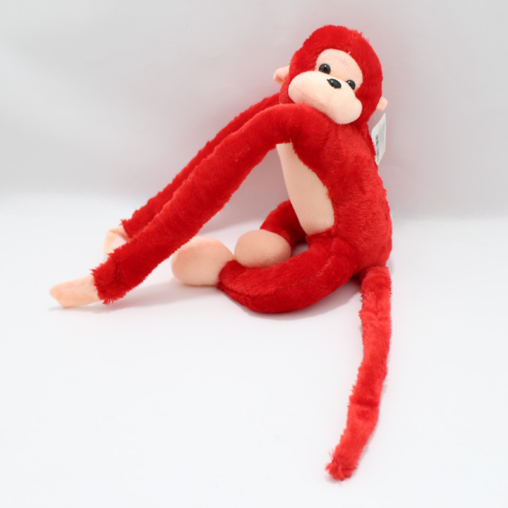 Peluche de mono rojo con extremidades largas y flexibles, cara y manos color crema, textura suave, ideal para decorar habitaciones infantiles.