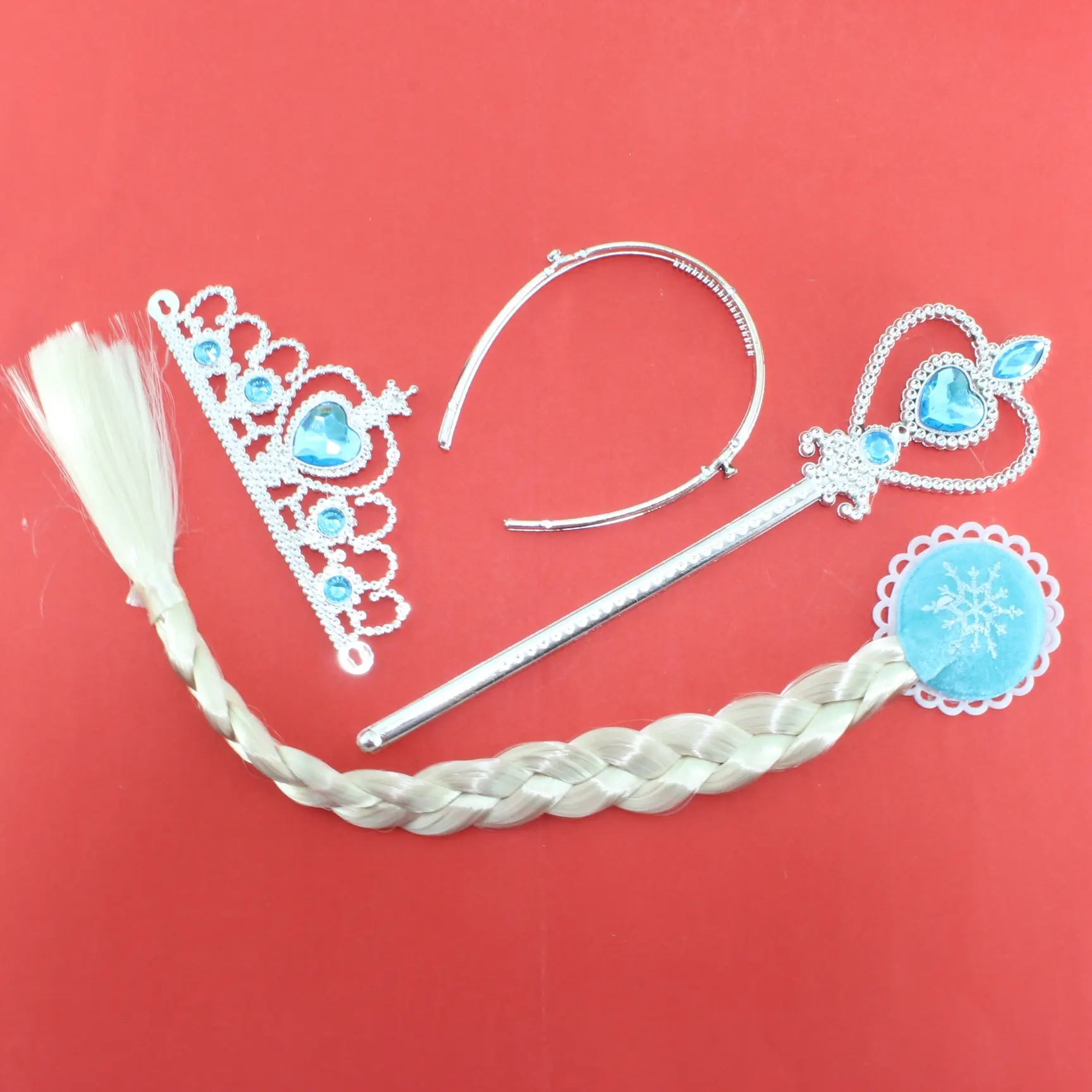 Set de accesorios Frozen plateados con trenza rubia, corona, diadema y cetro con gemas azules sobre fondo rojo.