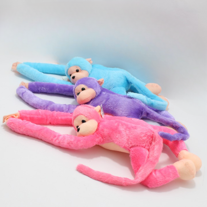 Tres peluches de mono con extremidades largas y flexibles en colores azul, morado y rosado, con textura suave y detalles en beige.