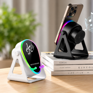 Parlante amplificador pasivo con carga inalámbrica y luz LED, disponible en blanco y negro, sosteniendo un smartphone sobre libros en una mesa de madera.