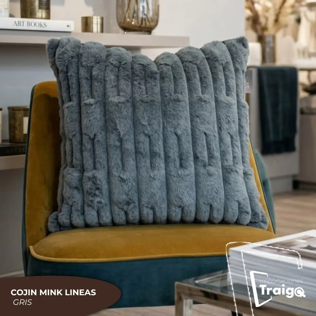 Cojín Mink gris de textura suave con relieve de líneas verticales, sobre un sillón de terciopelo mostaza.