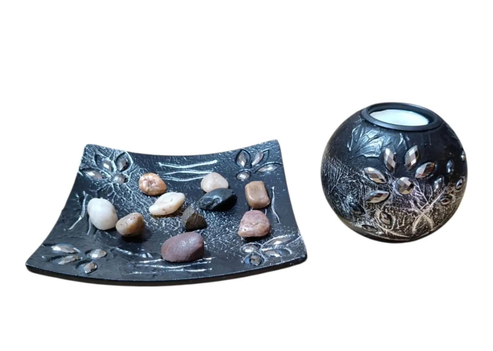 Set decorativo de resina negra con relieves florales plateados: base cuadrada con piedras de colores y portavelas esférico.