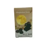 Empaque de proyector de estrellas y planetas con diseño de luna amarilla, dispositivo negro y tres discos de proyección intercambiables.