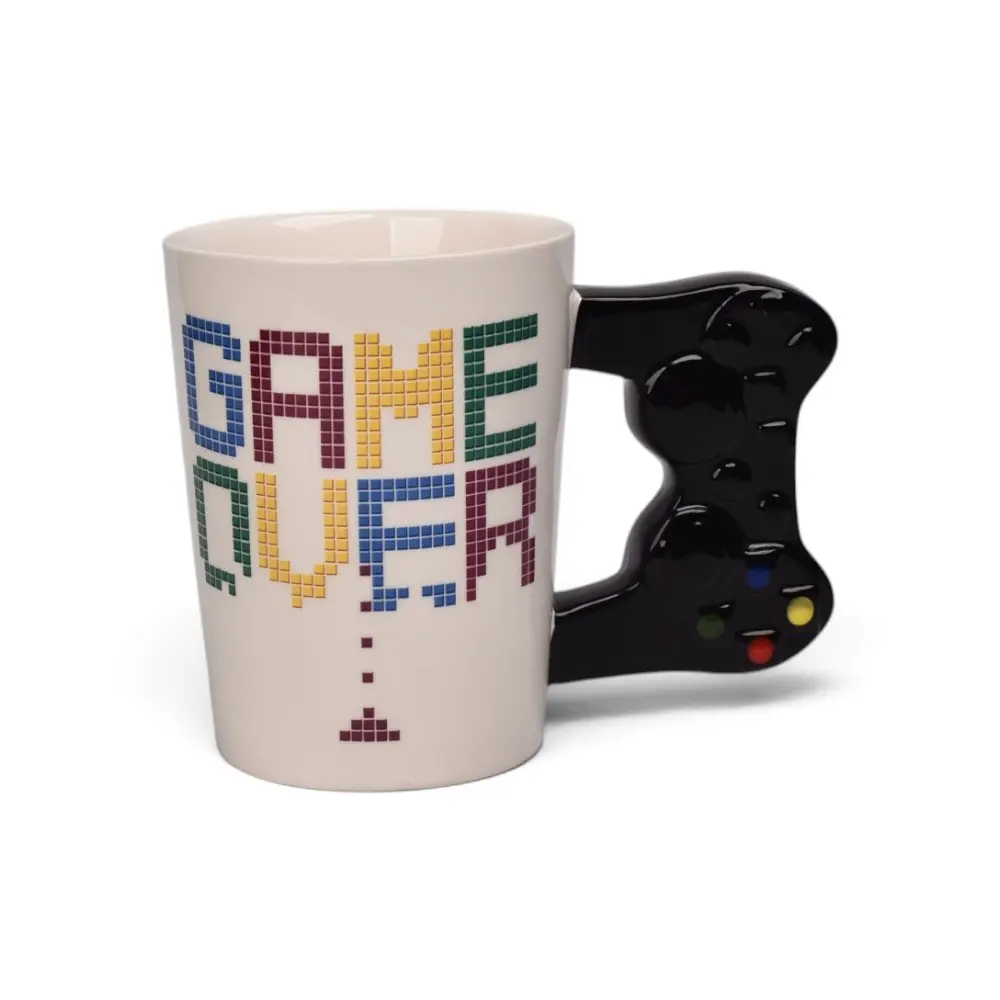 Taza de cerámica blanca con frase pixelada "Game Over" de colores y asa negra en forma de control de video juego.