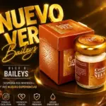 Vela hidratante para masaje con aroma a Baileys, en frasco con tapa dorada y caja naranja decorativa sobre un pedestal brillante y elegante.
