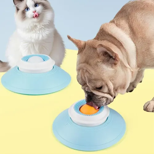 Comedero interactivo lento azul con base antideslizante y bola central texturizada, usado por un gato blanco y un perro beige.