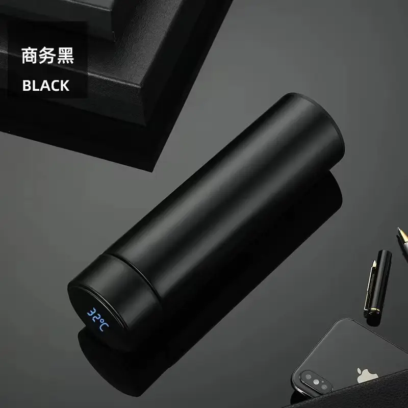 Termo de acero inoxidable negro mate con pantalla LED que muestra 32°C en la tapa, sobre superficie oscura junto a un celular y un bolígrafo.