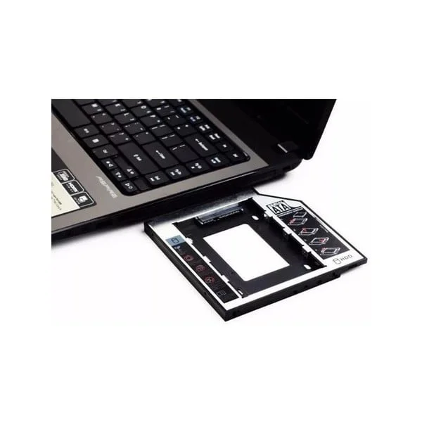 Caddy adaptador de disco duro HDD o SSD negro y plateado junto a una laptop abierta para expandir el almacenamiento interno del equipo.