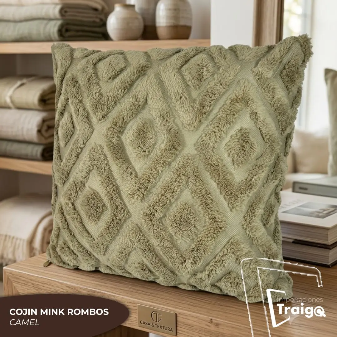 Cojín decorativo color camel con textura de rombos en relieve, acabado suave tipo mink, exhibido sobre una superficie de madera en un entorno hogareño.