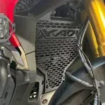 Protector de radiador de acero inoxidable con patrón hexagonal y diseño X-ADV calado, instalado en una motocicleta Honda X-ADV.