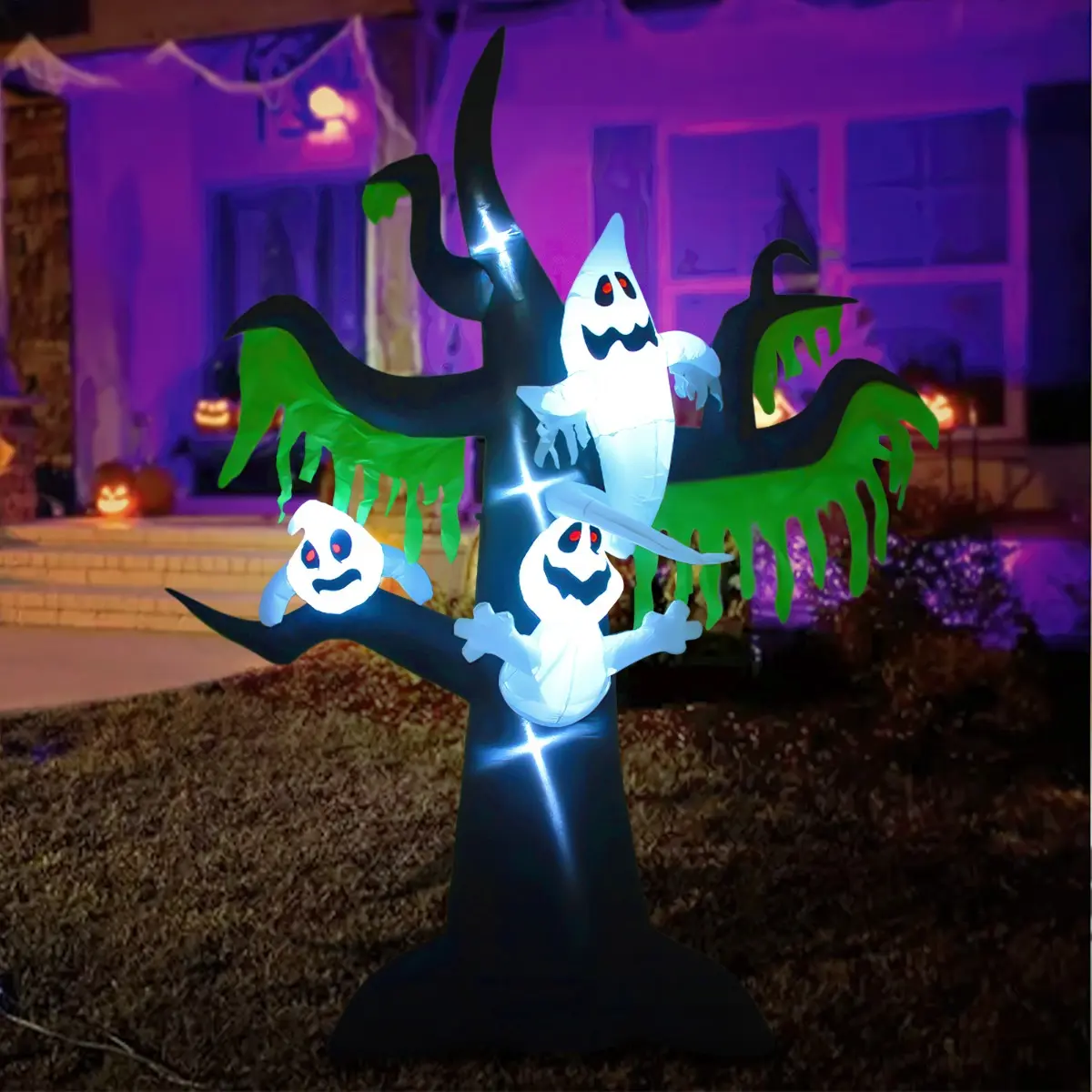 Árbol inflable de Halloween negro con follaje verde, tres fantasmas blancos de ojos rojos y luces LED brillantes en un jardín nocturno.