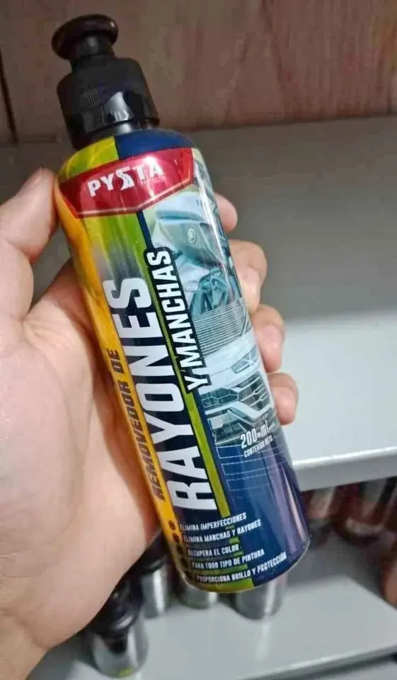 Mano sosteniendo envase plástico de 200 ml de removedor de rayones con dispensador negro, etiqueta multicolor y texto en español.