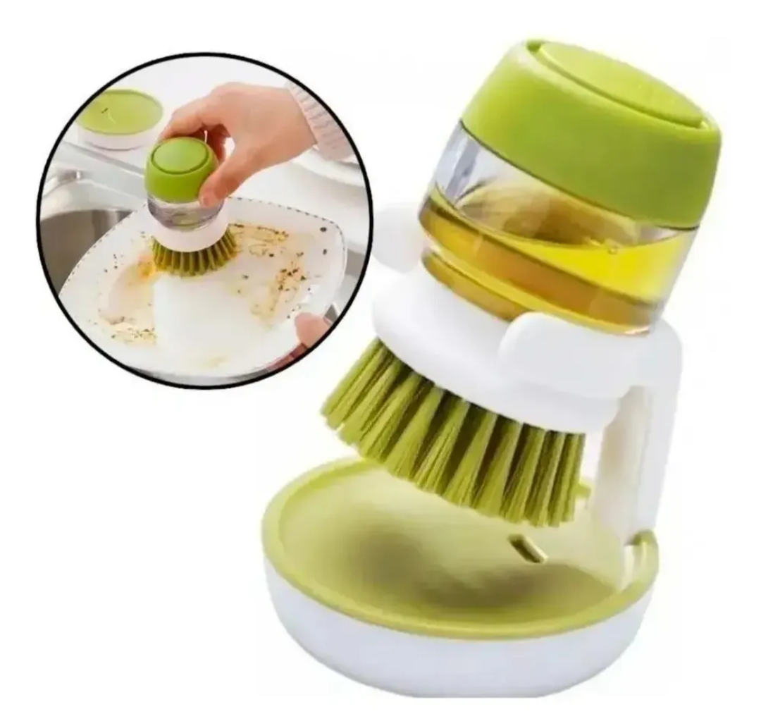 Cepillo fregador de cocina con cerdas verdes y dosificador transparente para jabón, apoyado sobre su base blanca.