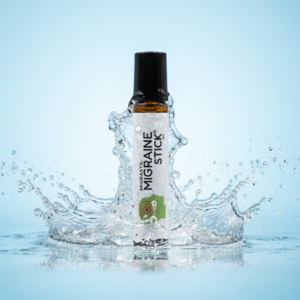 Roll-on de aromaterapia para migraña de envase ámbar con etiqueta blanca, rodeado por un salpicadura de agua sobre fondo celeste.