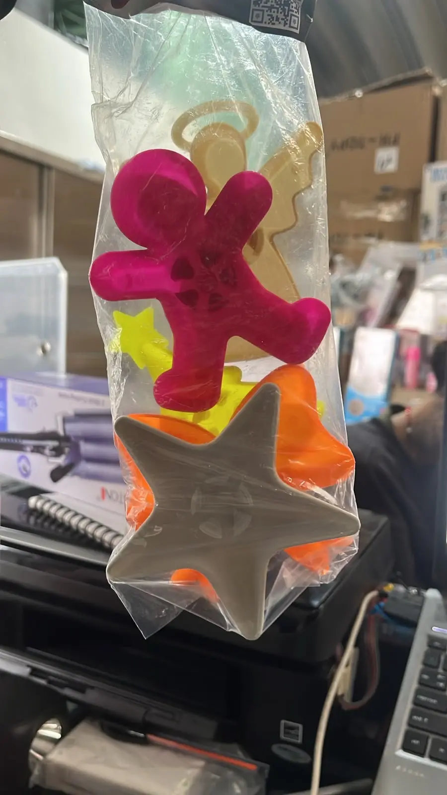 Bolsa plástica con cinco soportes para velas de repostería en colores fucsia, beige, amarillo, naranja y gris con formas variadas.