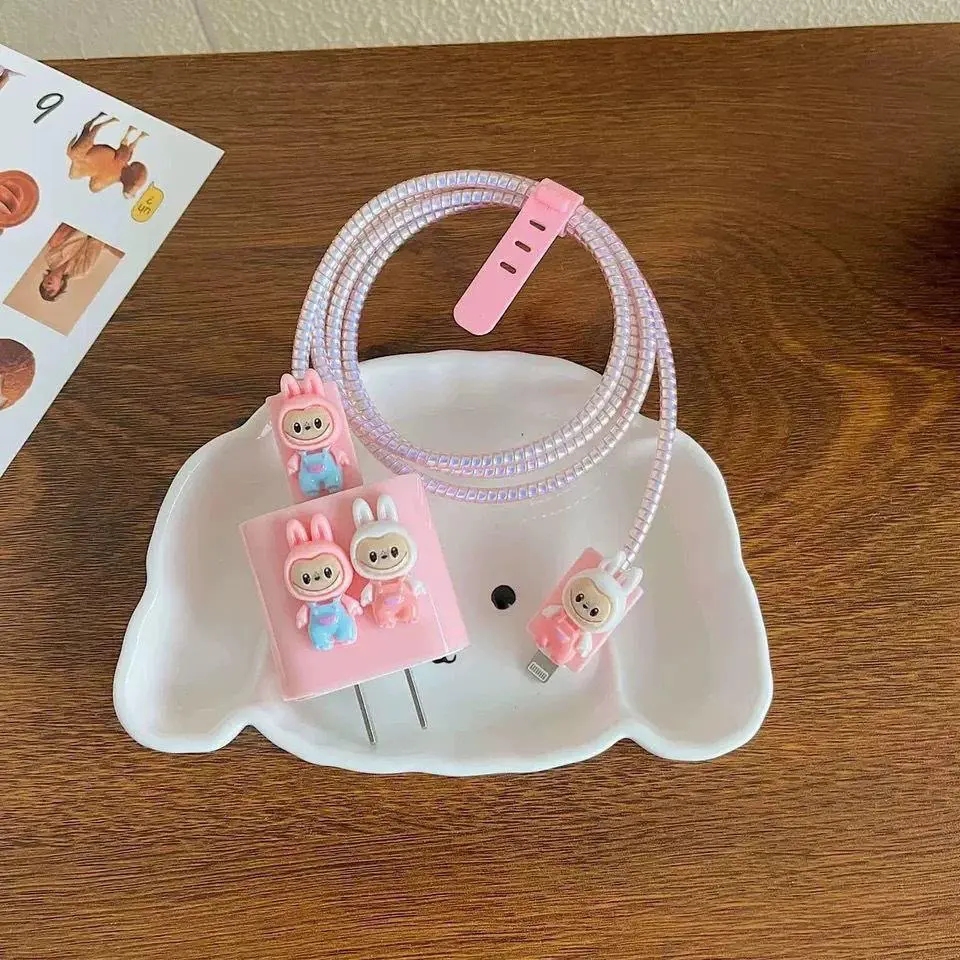Set de cargador y cable con protector de silicona rosa, decorado con figuras de conejitos, sobre un plato de cerámica blanco con forma de perrito.