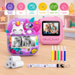 Cámara instantánea infantil morada con diseño de unicornio, rollo térmico imprimiendo familiar, tres rollos de papel, cinco marcadores de colores y correa estampada sobre mesa de madera.