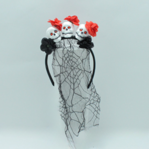 Diadema gótica negra con tres calaveras blancas de ojos rojos, flores rojas, flores negras y un velo traslúcido con telaraña.